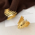 Detailopname van goudkleurige golvende oorknopjes op een bruine gebreide achtergrond - Goud