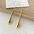 Makroaufnahme goldener Tropfenohrringe mit hochglanzpolierter Oberfläche und flüssigem Design - Gold