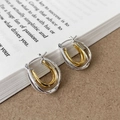 Eleganti orecchini a cerchio a U multistrato bicolore oro e argento su sfondo di libro - Bicolore Oro e Argento