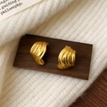 Dettaglio ravvicinato di orecchini a conchiglia dorati opachi con design ondulato - Oro