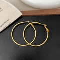 Detailed view of large golden hoop earrings with high-polish finish on natural linen - Gold 1.5cm x 40mm