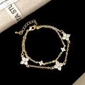 Macro shot of gold double-layer bracelet with sparkling zircon four-leaf clover charms - Gold
