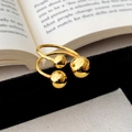 Détail d'une bague à boules dorées polies sur un présentoir en velours noir - Bague Petite Sphère Dorée