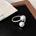 Detail van gedraaide zilveren ring met dubbele parels op een elegante achtergrond - Enkele Laag Stijl / Zilver