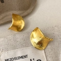 Dettaglio ravvicinato di orecchini curvi dorati con finitura in metallo spazzolato - Oro