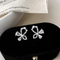 Detalle de pendientes de lazo con perlas blancas y circonitas brillantes talladas - Pendientes de Botón Plateados con Lazo