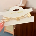 Close-up of golden double-layer bracelet with cat eye stone and clover charms - Gold
