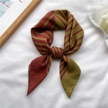 Red and olive green striped silk scarf tied in a bow on a white fabric background - Brown