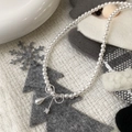 Elegant pearl bow necklace with droplet pendant displayed on a winter festive background - Bright Pearl Bow Necklace