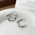 Macro detail of twisted silver earrings on a ceramic dish with French minimalist decor - Silver