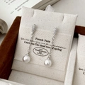 Detalle de pendientes de perlas con circonitas y borlas largas de plata en una tarjeta - Plateado
