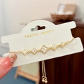 Detail of adjustable gold bracelet with clover charms and white mother of pearl inlay - Gold