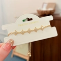 Dettaglio di un bracciale a stella dorato con zirconi e catena a trazione regolabile - Stile Stella Cava / Oro