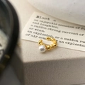 Dettaglio di un ear cuff dorato con perla su un supporto decorativo - Oro
