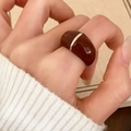 Roter Retro-Ring aus Kunstharz mit Silberlinien am Modell auf beigem Hintergrund - Dunkelrot