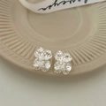 Detail of silver pleated flower stud earrings featuring shimmering crystal center accents - Silver