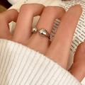 Nahaufnahme eines silbernen offenen Rings mit Tropfenenden über einem weißen Strickpullover - Silberner Wassertropfen-Stil (C-315)