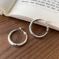 Eleganti orecchini a cerchio in argento martellato su tavolo in legno e libro - Orecchini a Cerchio con Trama Martellata (A-1893)
