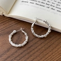 Eleganti orecchini a cerchio in argento intrecciato su scrivania in legno con libro d'epoca - Orecchini a Cerchio con Trama a Corda Intrecciata (A-1107)