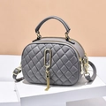 Elegante bolso acolchado gris con herrajes dorados y un colgante de borla moderno - Gris