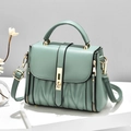 Bolso bandolera verde menta con textura plisada en V y detalles dorados sobre pedestal - Verde