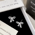 Nahaufnahme von silbernen Schleifen-Ohrsteckern mit Zirkonia-Steinen in einer Box - Band Schleifenstil (A-1296)