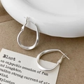 Macro view of matte silver irregular twisted hoop earrings on textured brown paper - Matte Silver Hoop Earrings