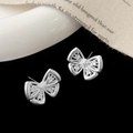 Detalle de pendientes de mariposa plateados con alas caladas y circonitas brillantes - Pendientes de Botón de Lazo Hueco Plateado (A-622)