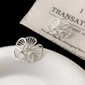Detalle macro de pendientes de flores plateadas con diseño hueco sobre un plato blanco - Pendientes de Botón de Flor Hueca Plateada (A-291)