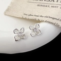 Detalle de pendientes de flor hueca de plata con circón sobre borde de cerámica - Pendientes de Botón de Flor Hueca Plateada (A-1551)