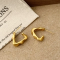 Macro shot of matte gold irregular wave earrings on natural linen and wood surface - Irregular Wave Line Style (A-1828)