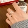 Close-up of a minimalist silver wavy band ring worn on a finger in a refined setting - Irregular Wave Style (C-194) / Silver
