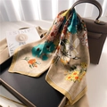 Elegante sciarpa in seta albicocca con fiori blu e arancioni drappeggiata su una borsa - Cachi
