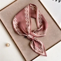 Detailansicht eines rosa Seidenschals mit Kettenmuster auf Tablett mit Perlen - Altrosa Geometrische Kette