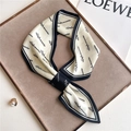 Detail of a tied ribbon scarf with navy borders and letter print on a display tray - 76x13cm / Navy Blue Print