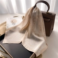 Detail of silk square scarf with paisley pattern draped over a luxury leather handbag - Khaki