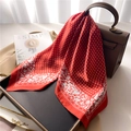 Close-up of red silk scarf with rose pattern and diamond grid on a brown leather bag - 70x70cm / Brown Red