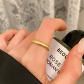 Elegante anello dorato con texture plissettata e zircone bianco sulla mano della modella - Stile Increspato Orizzontale (C-371) / Oro