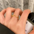 Dettaglio di un anello dorato ondulato minimalista su uno sfondo estetico curato - Stile Minimalista a Onde (C-380) / Oro