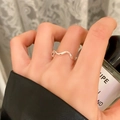 Primo piano di un anello minimalista a onda in metallo argento lucido sull'indice - Stile Minimalista a Onde (C-380) / Argento