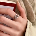 Detailopname van een zilveren meerlaagse kruisring op een hand voor een minimalistische look - Zilver Gekruiste Stijl (C-20)