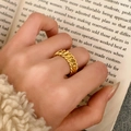 Close-up of a gold-plated chunky chain link ring styled on a finger over a book - Gold - Braided Chain Style (C-430)