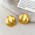 Macro shot of gold matte round earrings with water ripple texture on linen fabric - Rippled Disc Style (A-1838)