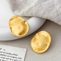 Macro detail of gold brushed metal earrings with irregular texture on a ceramic plate - Irregular Oval Disc Style (A-1751)