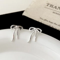 Macro view of elegant silver bow stud earrings with polished finish on a ceramic tray - Shiny Draping Bowknot Style (A-1213)