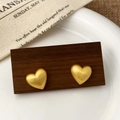 Detailed close-up of matte gold heart-shaped stud earrings with brushed metal texture - 3D Heart Style (A-1588)