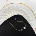 Close-up of gold-plated snake chain necklace with two elegant white pearls on a tray - Minimalist Double Pearl Style