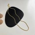 Dettaglio di una collana a catena a fune dorata minimalista su un cuscino nero elegante - Oro