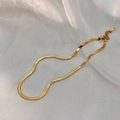 Close-up of gold double-layer flat snake bone necklace on white silk background - Gold Single Layer Necklace
