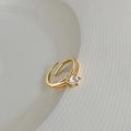 Nahaufnahme eines goldfarbenen Rings mit Zirkon-Hauptstein und seitlichem Steinbesatz - Zirkonia Geometrischer Offener Ring / Gold